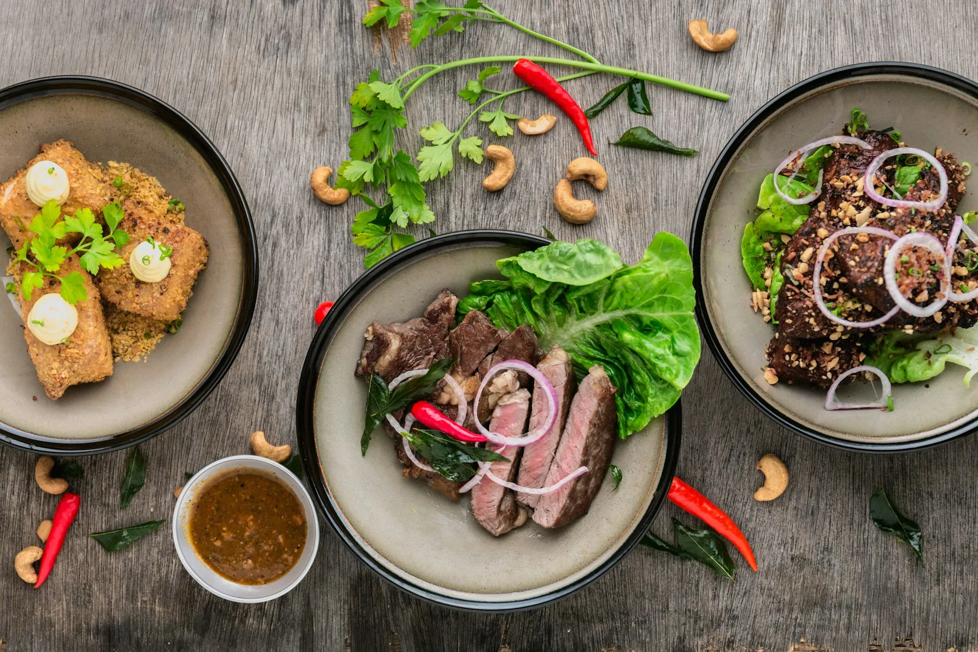 Plates of grilled meat and vegetables seen from above